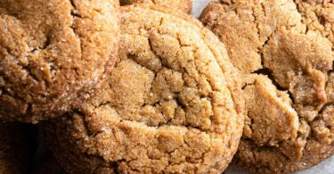 Des cookies au gingembre et à la cannelle sont empilés de manière aléatoire. On peut voir qu'ils sont enrobés d'une fine croûte de sucre.