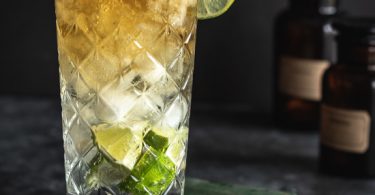 Un cocktail à base de rhum épicé dans un grand verre avec plein de citron vert