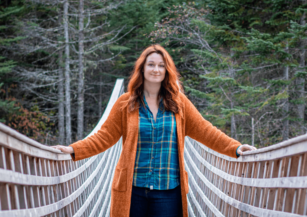 Jeune femme en chemise à carreaux sur un pont avec une forêt en arrière plan
