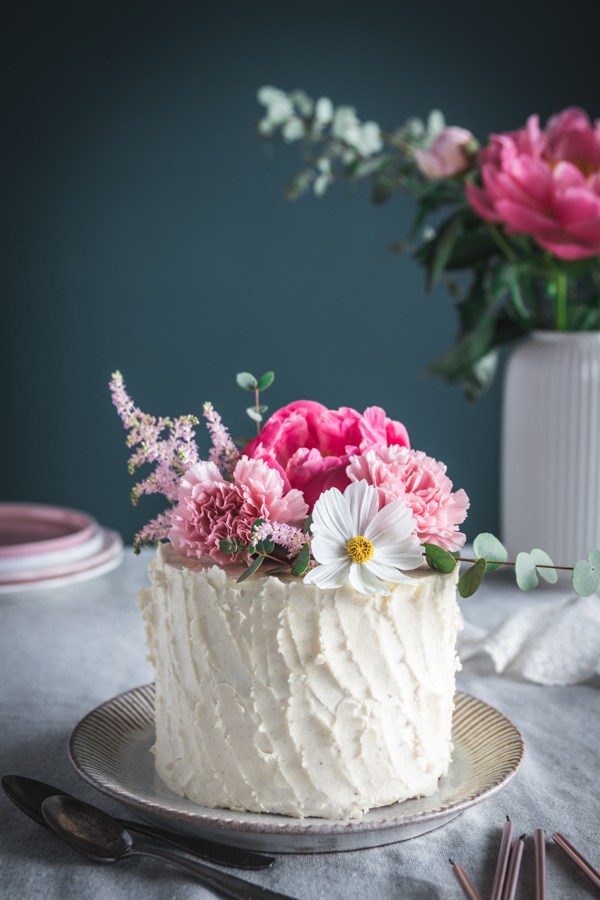 Layer cake vanille, fraise et rhubarbe, décoré de fleurs printanières vu de face.