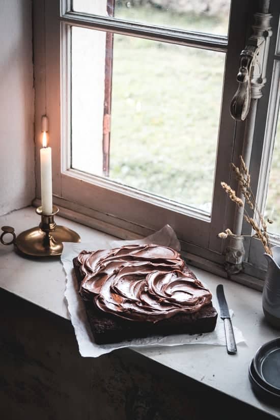 Scène hivernale autour d'un gâteau au chocolat photographié sur le bord d'une fenêtre. Le glaçage chocolat café est joliment disposé sur le dessus pour former des vagues.
